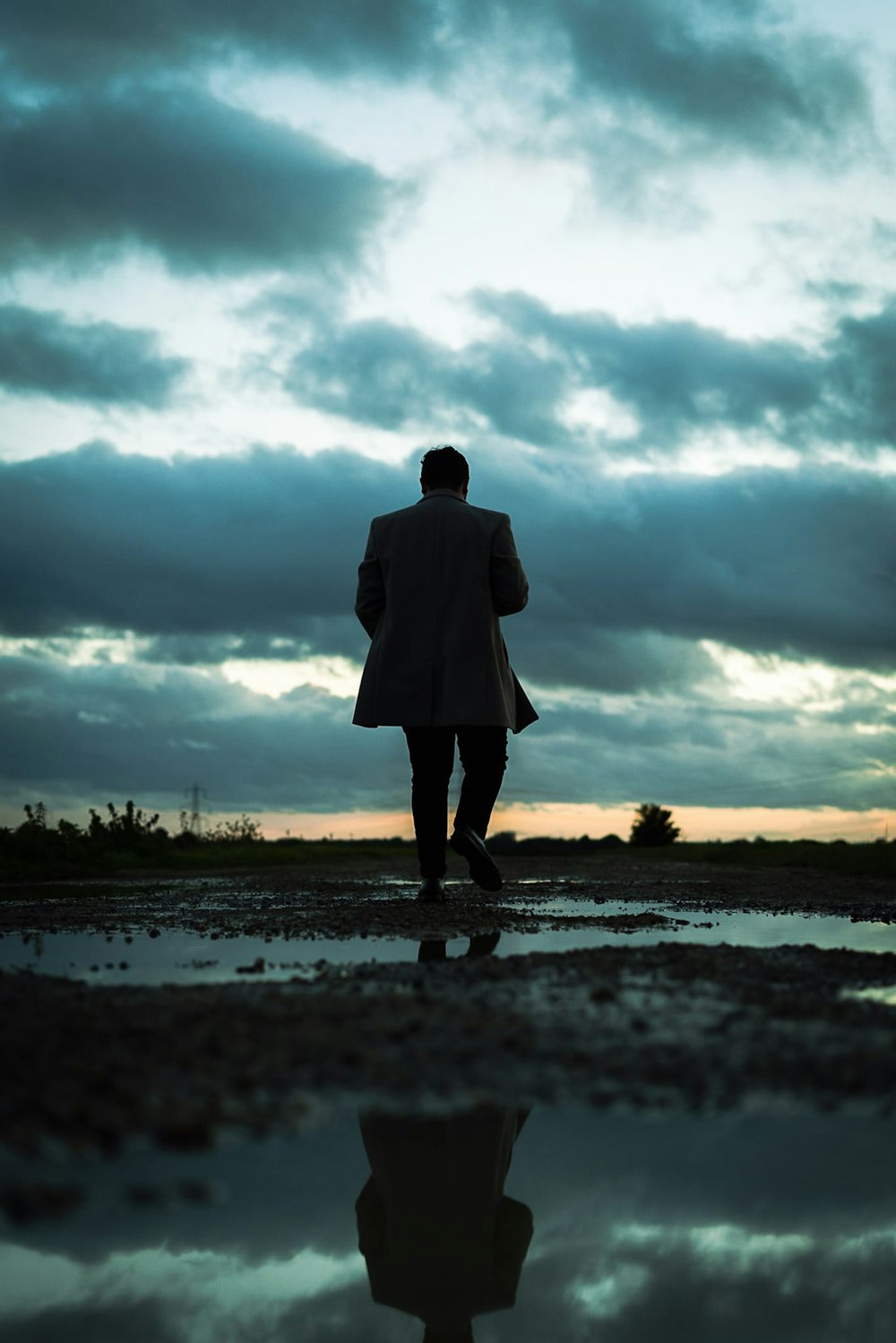 a man in a white coat walking across a puddle