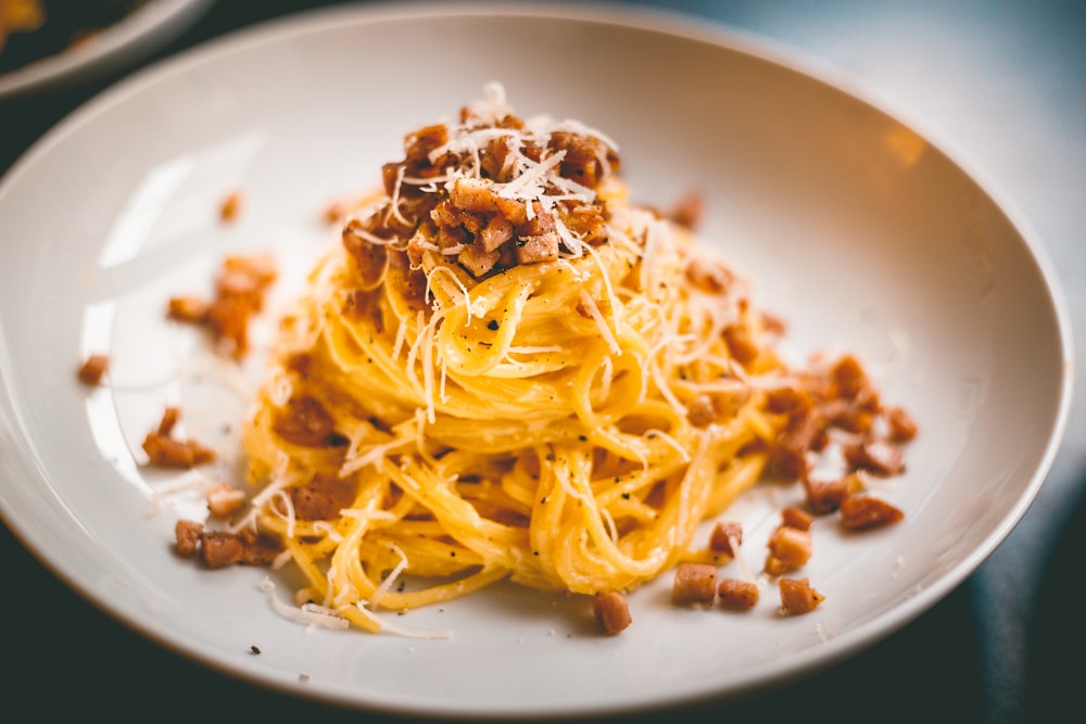 ein weißer Teller mit Spaghetti und Speck