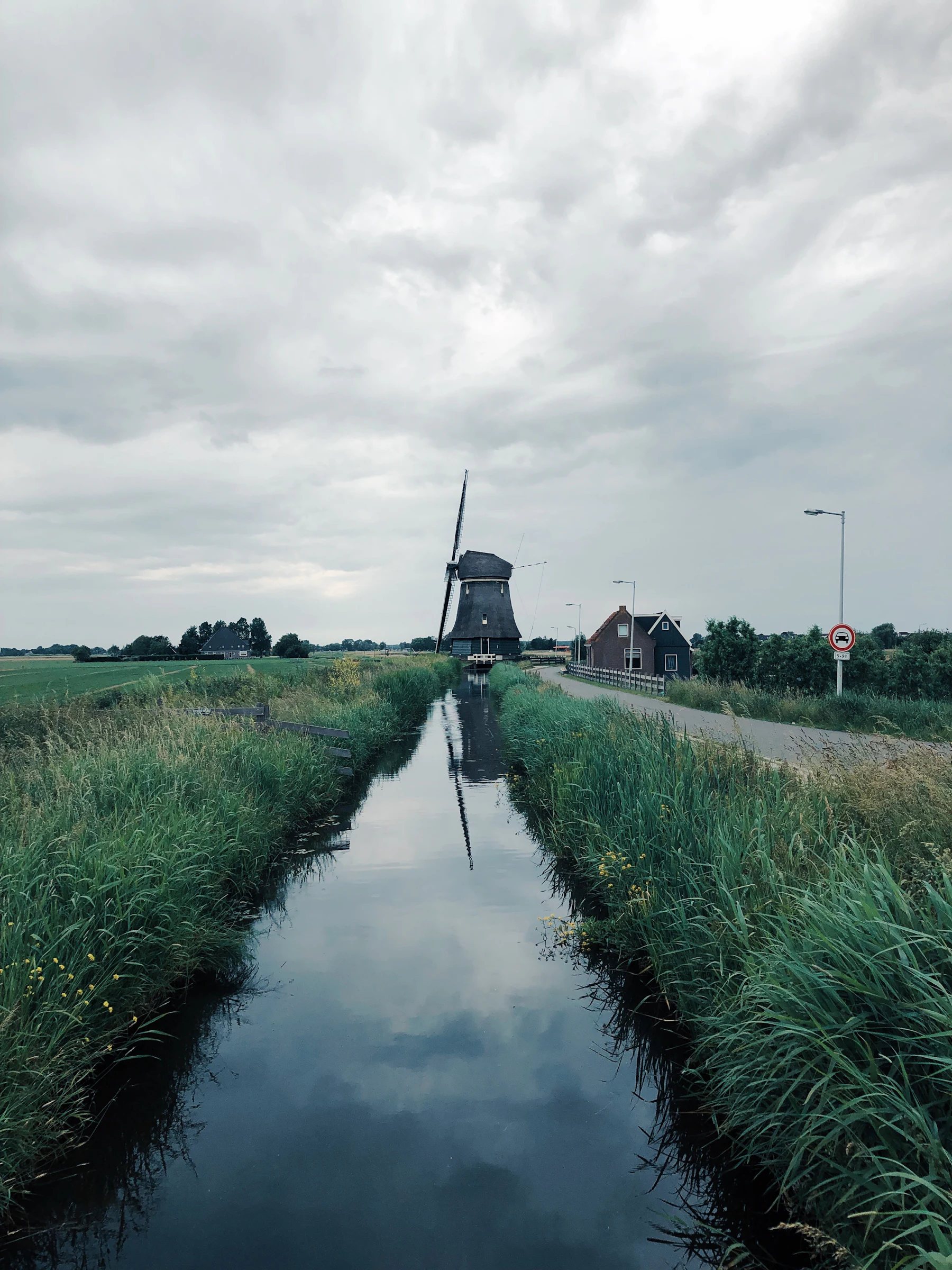 Windmühle am Ende eines geraden Kanals unter schwerem Himmel