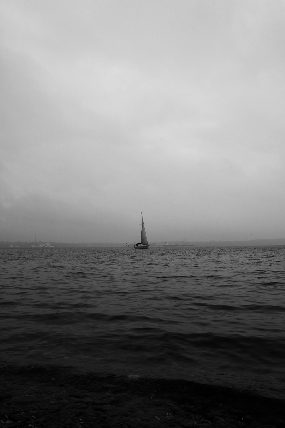 Una foto in bianco e nero di una barca a vela nell'oceano