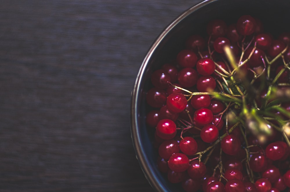 a metal bowl filled with red berries on top of a wooden table