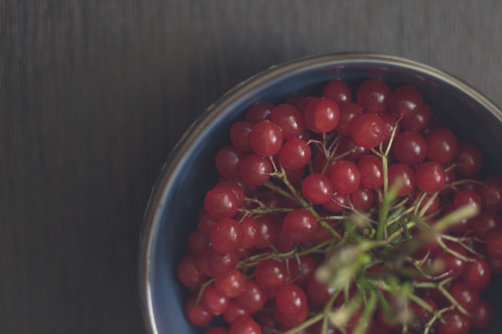 a blue bowl filled with red berries on top of a table