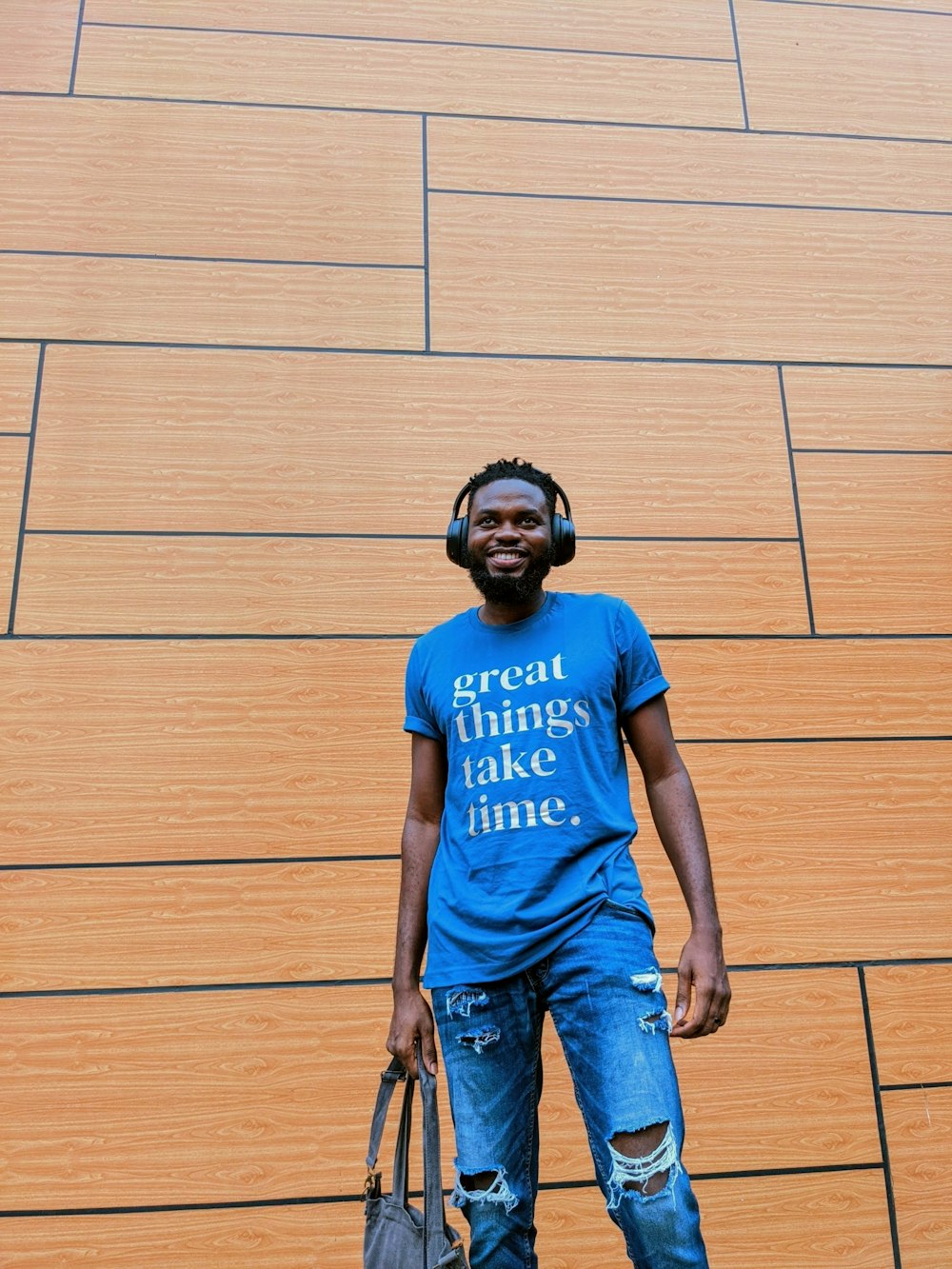 a man wearing headphones standing in front of a wooden wall