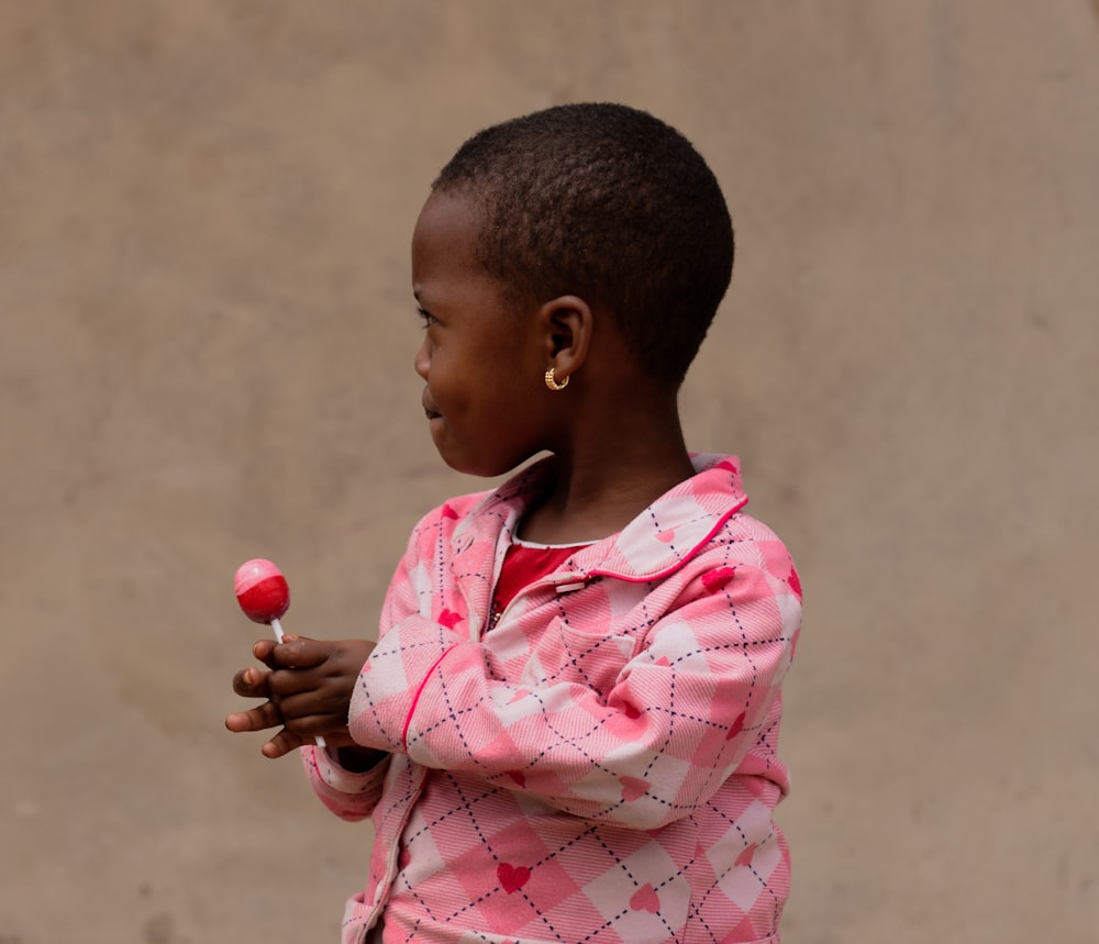 a little girl holding a red object in her hands