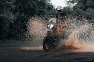 a man riding a motorcycle through a puddle of water