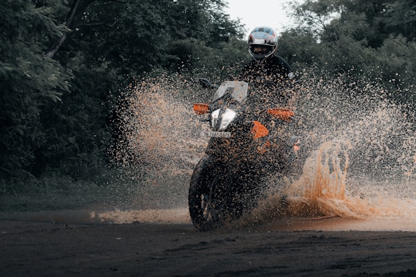 a man riding a motorcycle through a puddle of water