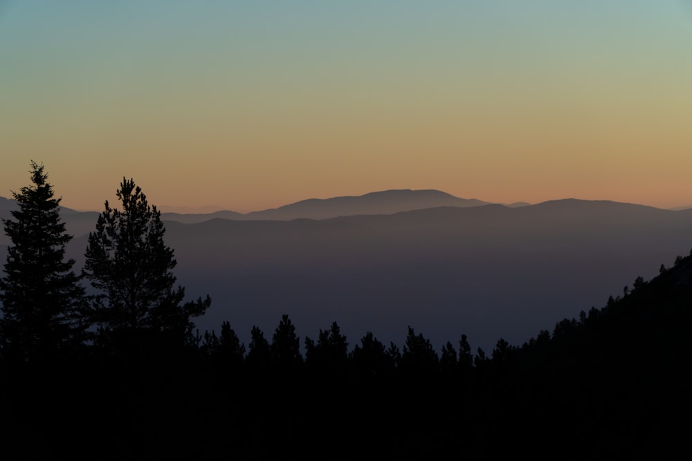 the sun is setting over a mountain range