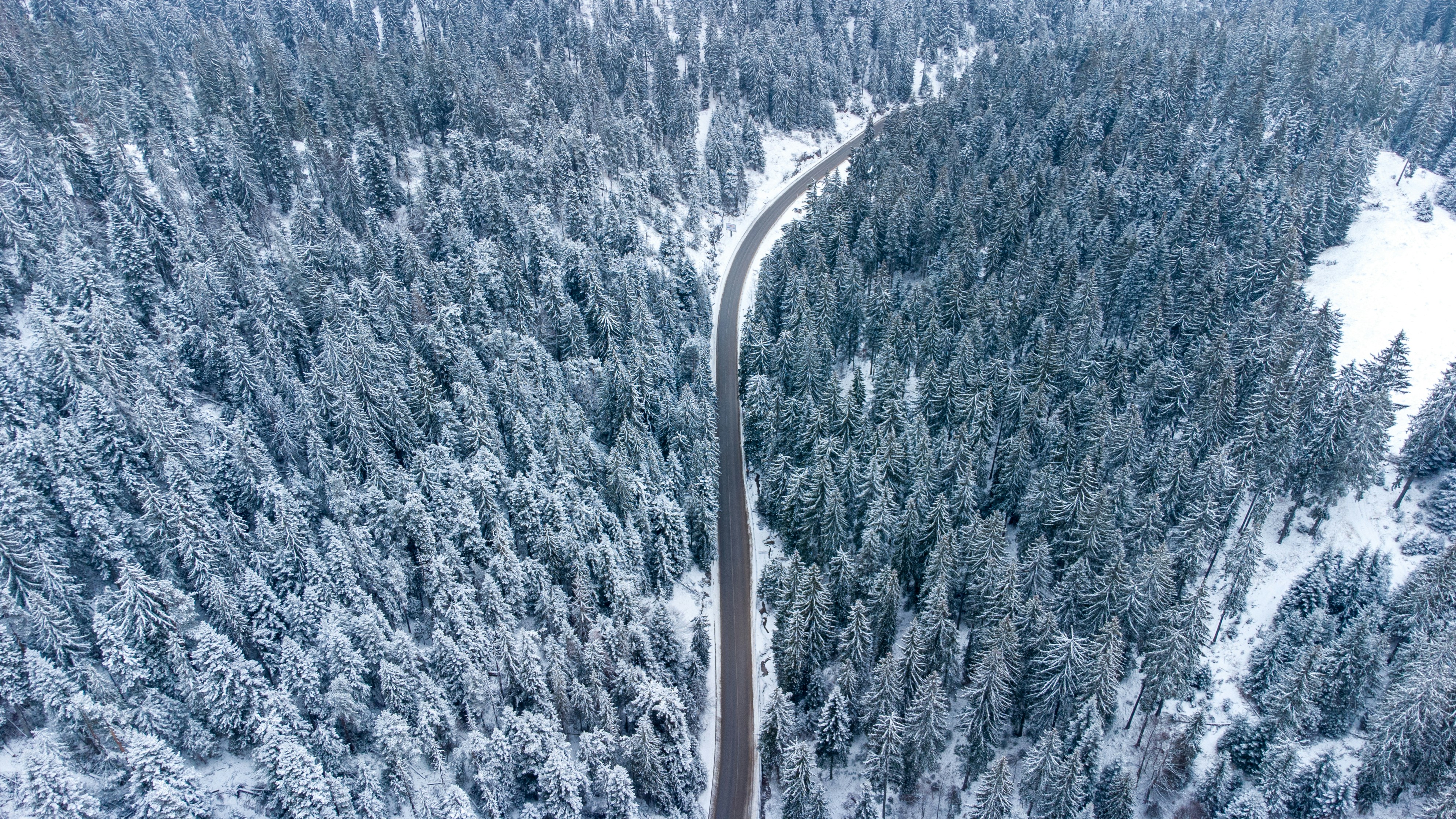 an aerial view of a road surrounded by snow covered trees, Path to the mountains.