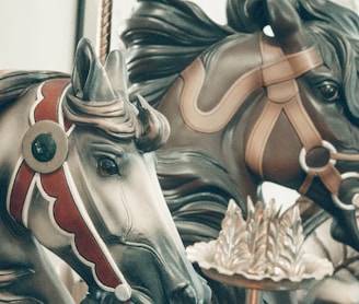 a close up of two horses on a carousel