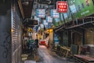 a narrow alley with signs hanging from the ceiling