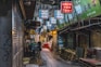 a narrow alley with signs hanging from the ceiling