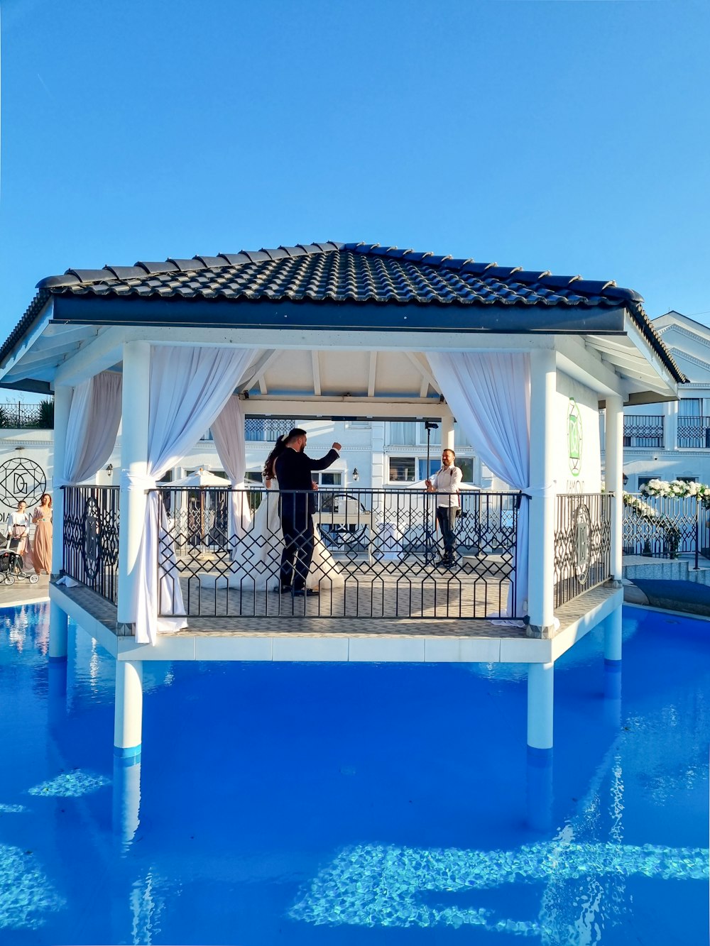 a man standing on a balcony next to a pool