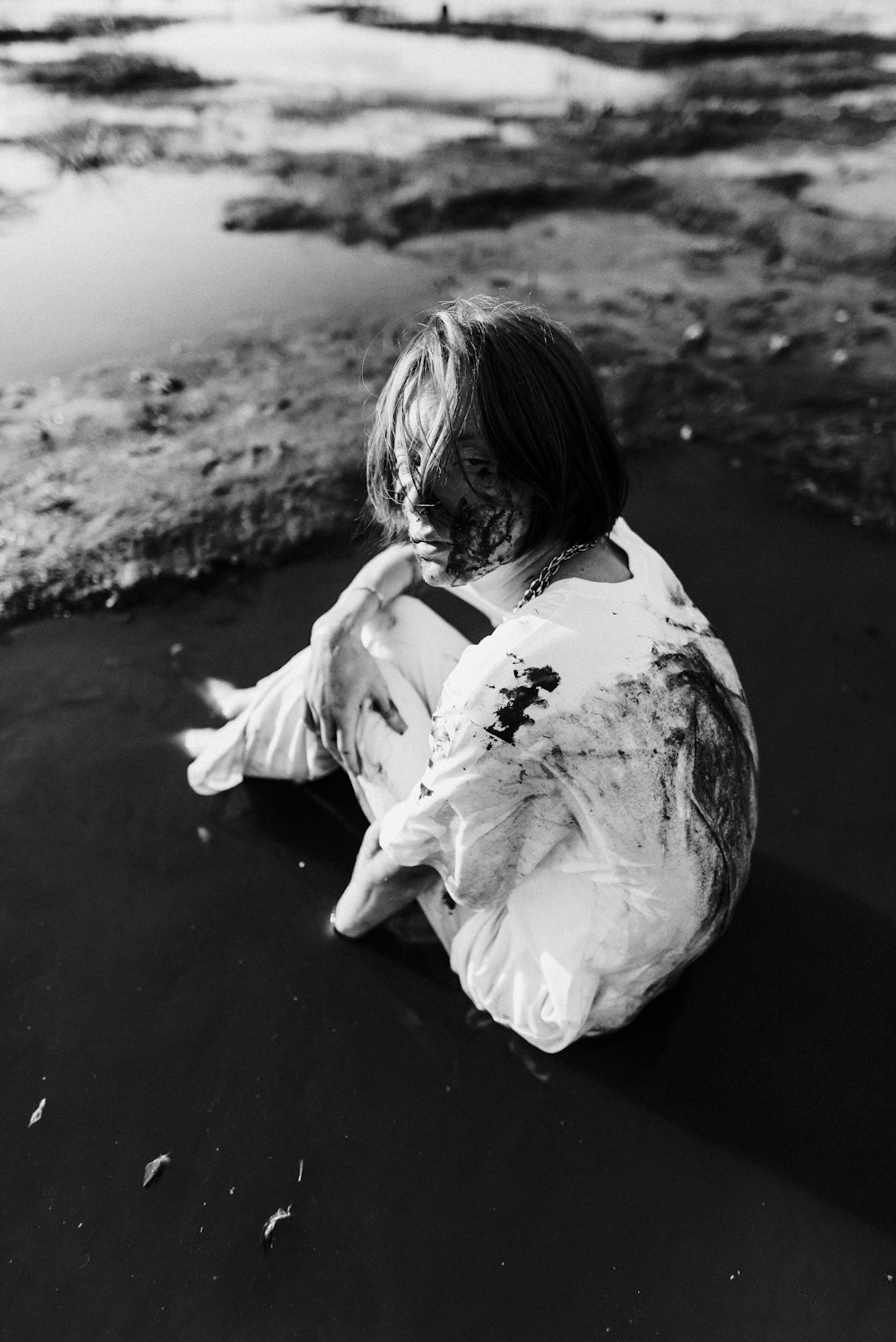 a black and white photo of a person sitting on the beach