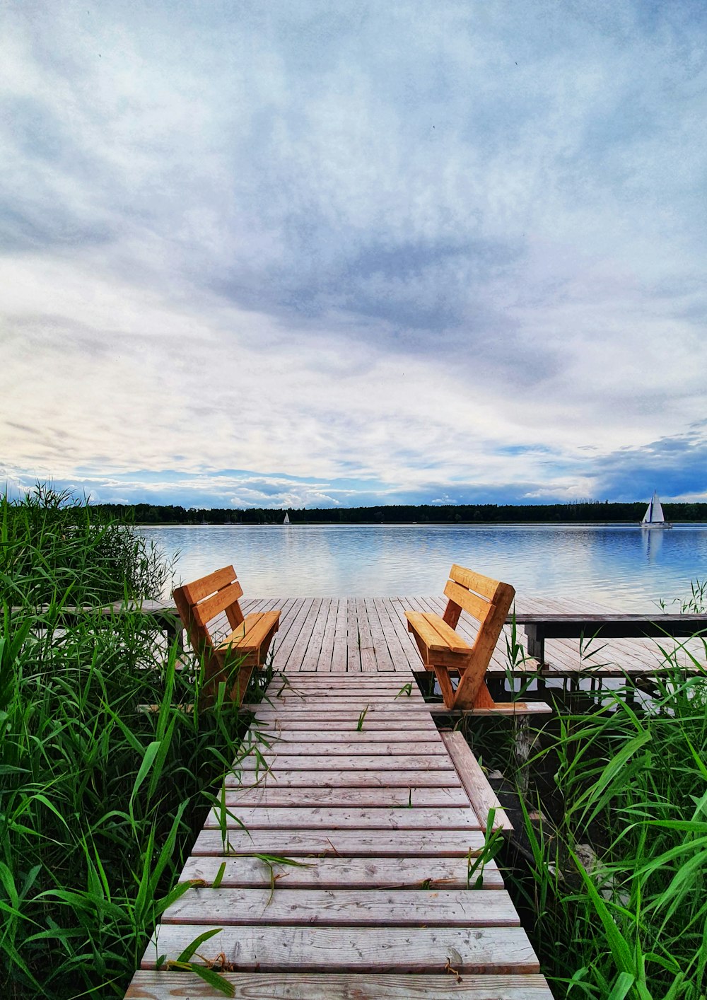 two wooden benches sitting on top of a wooden pier