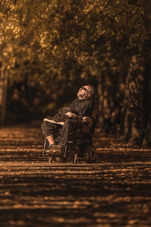 A smiling patient using a specialized wheelchair outdoors on a sunny day.