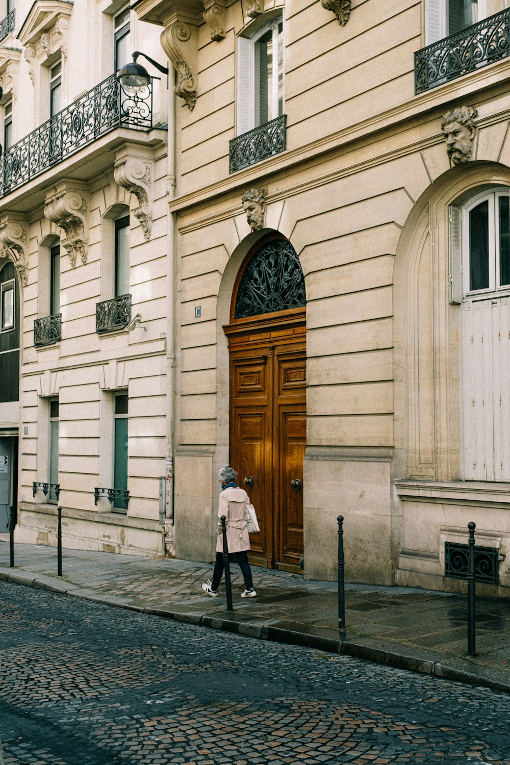 uma mulher andando por uma rua passando por um edifício alto