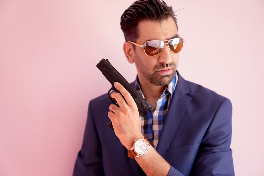 a man in a suit and sunglasses holding a gun