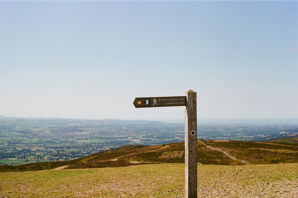 a wooden sign on top of a grass covered hill