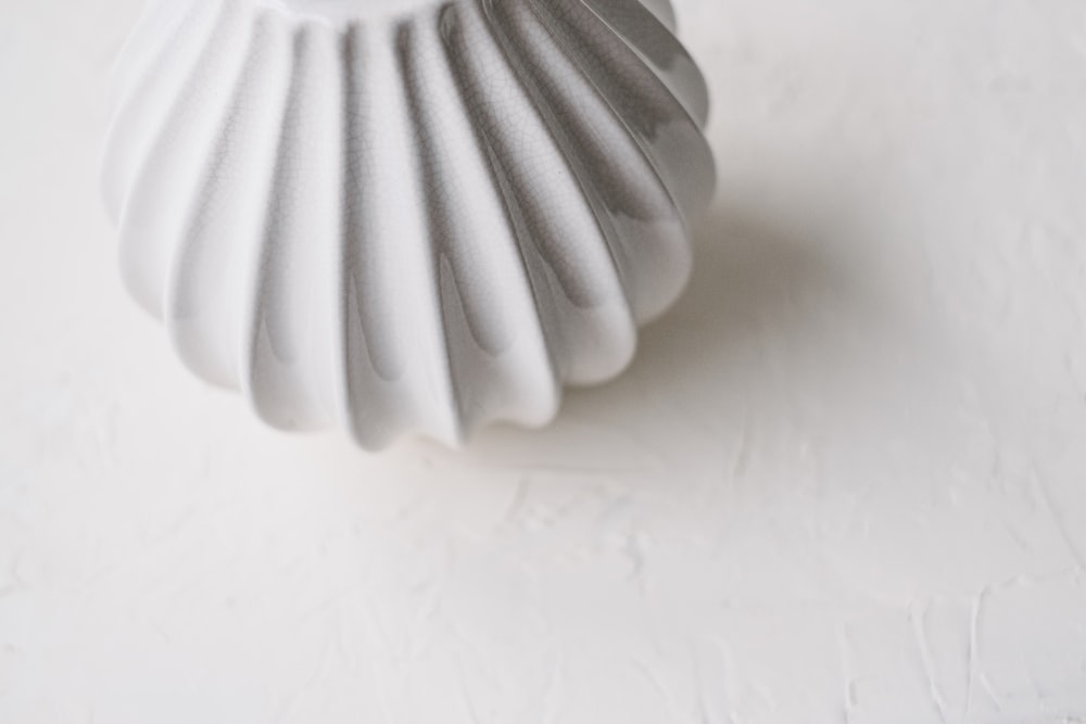 a white vase sitting on top of a white table