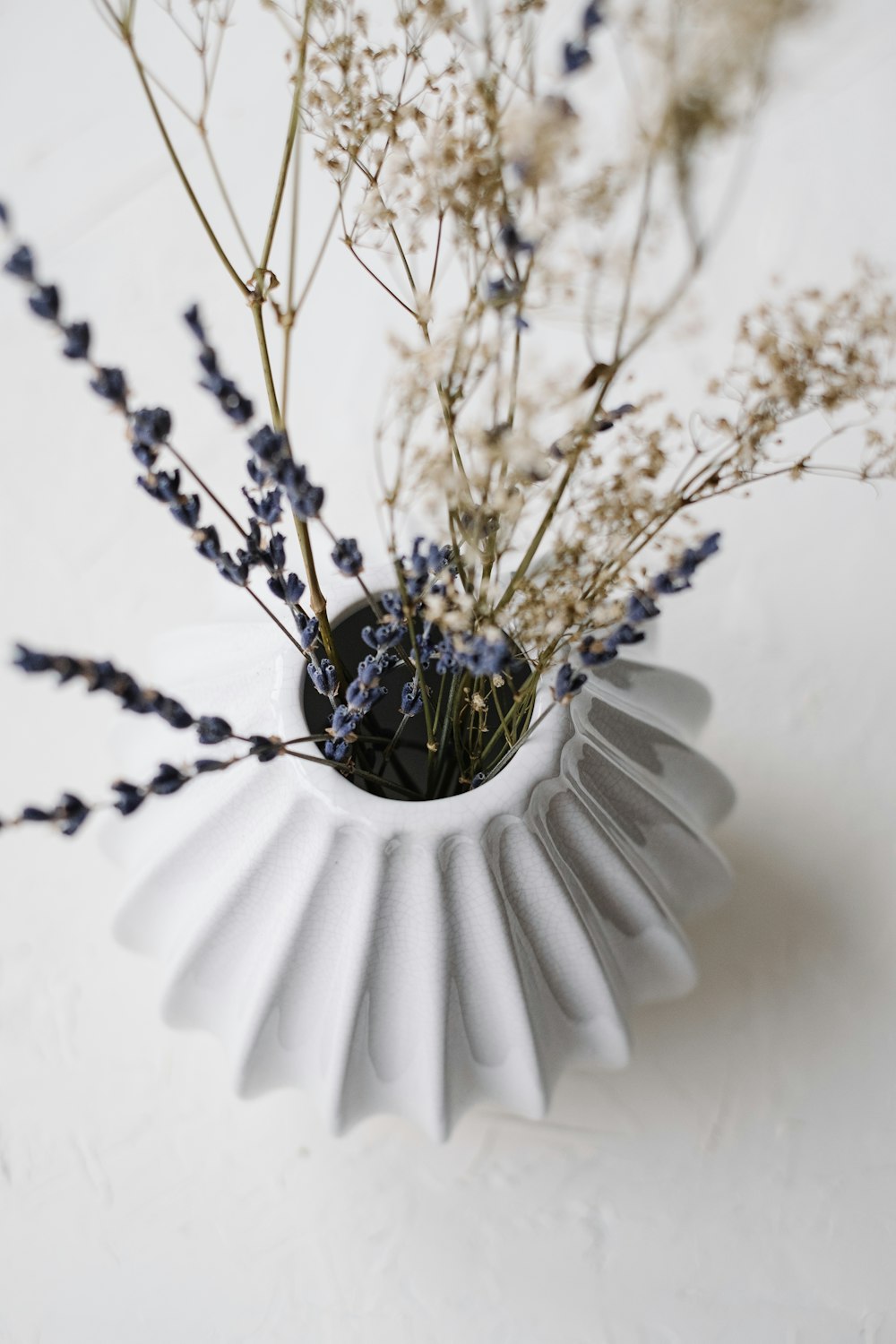 a white vase filled with purple flowers on top of a table