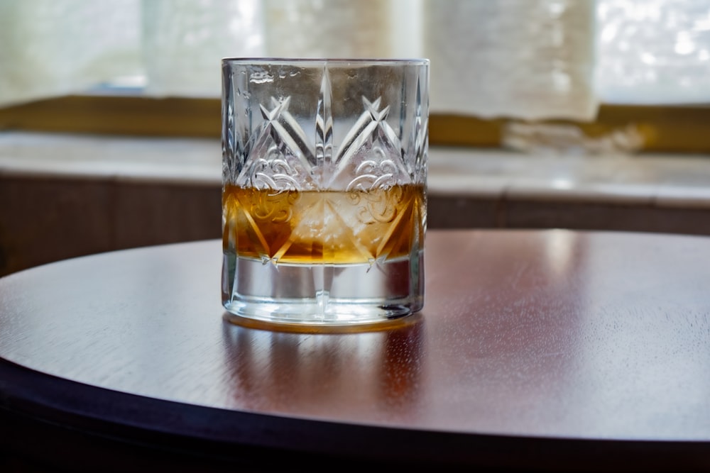 a glass of whiskey sitting on top of a wooden table