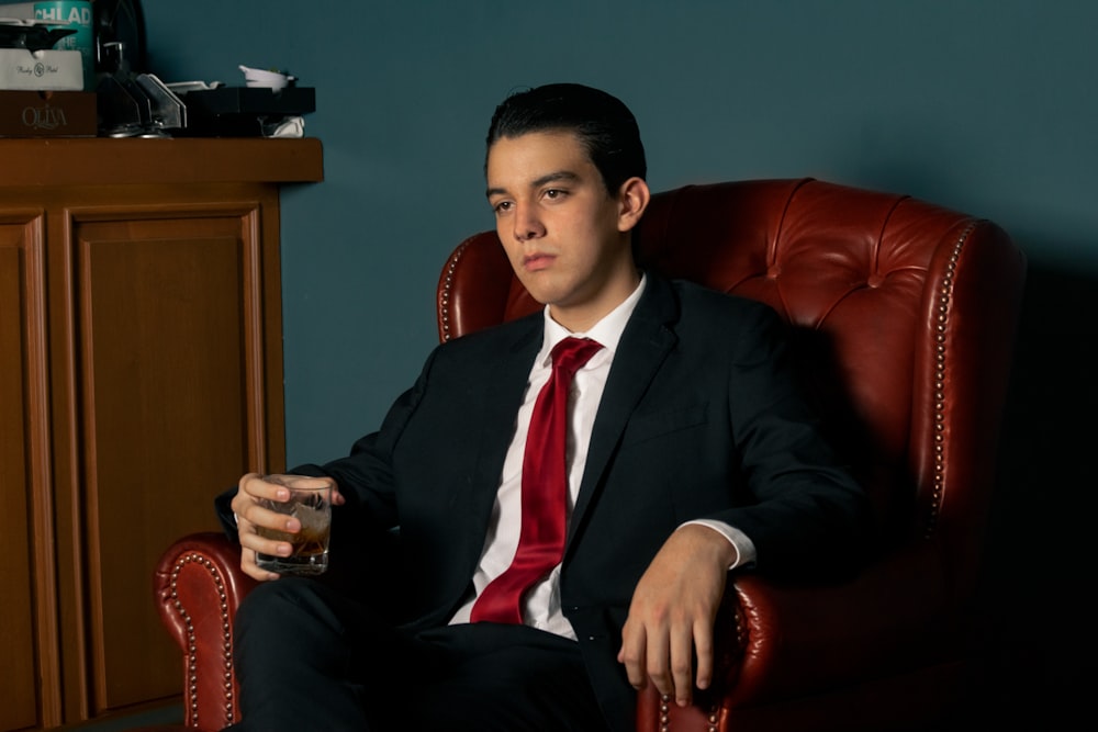 a man in a suit and tie sitting in a chair