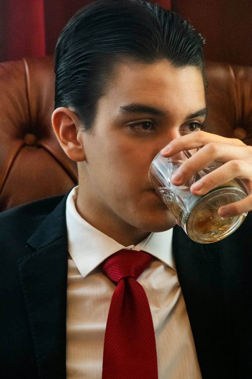 a man in a suit drinking from a glass
