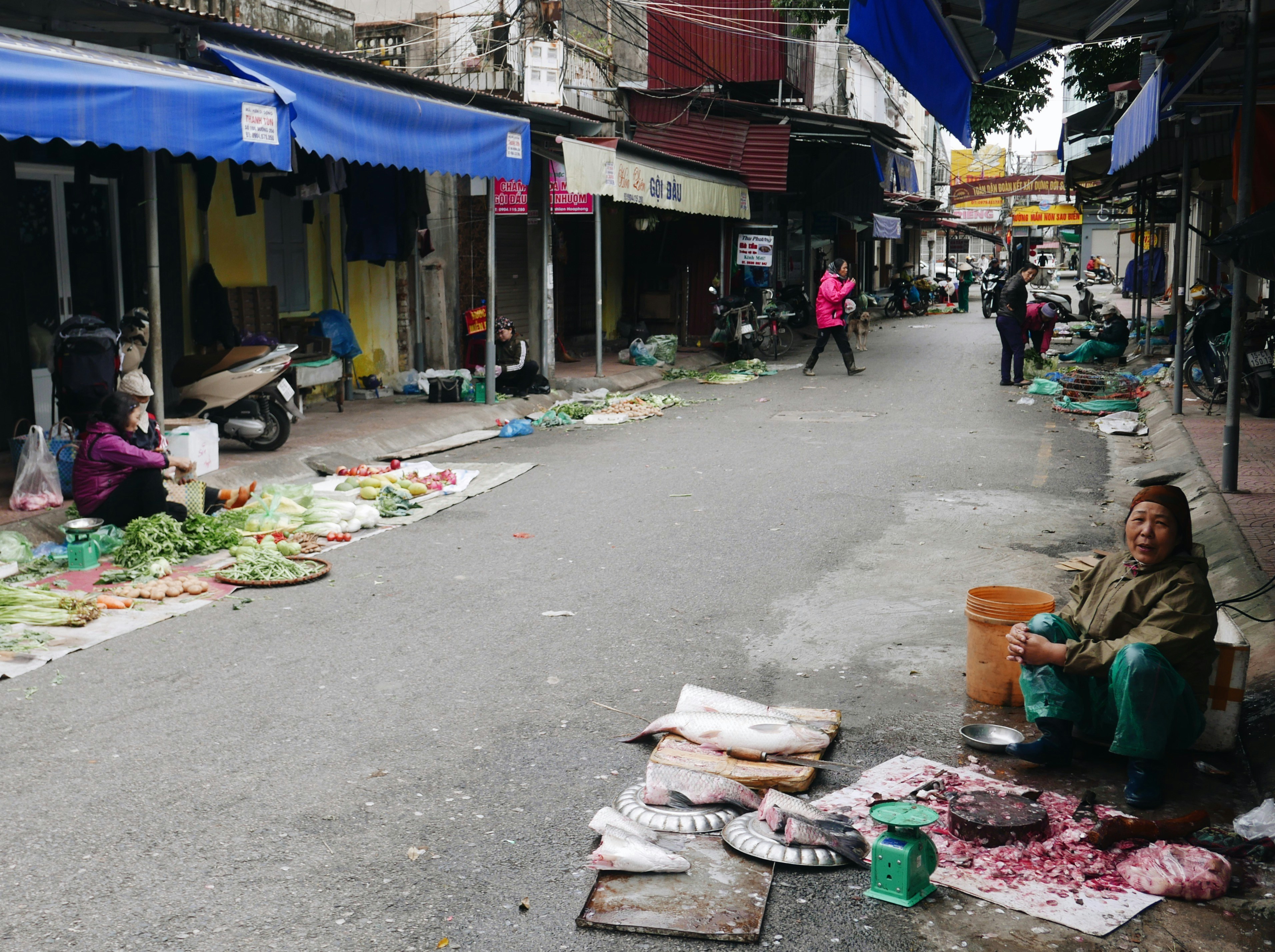 a woman sitting on the side of a road next to a pile of food