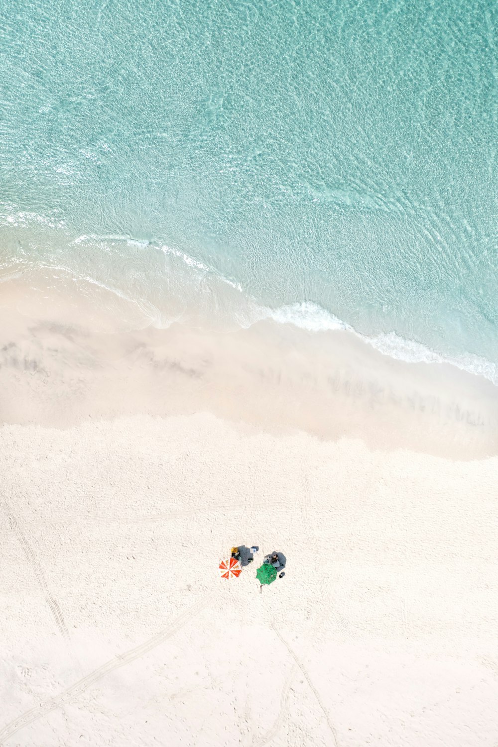 um par de guarda-sóis sentados em cima de uma praia de areia