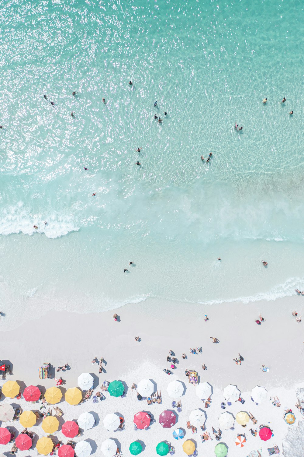 uma praia cheia de muita gente e guarda-sóis