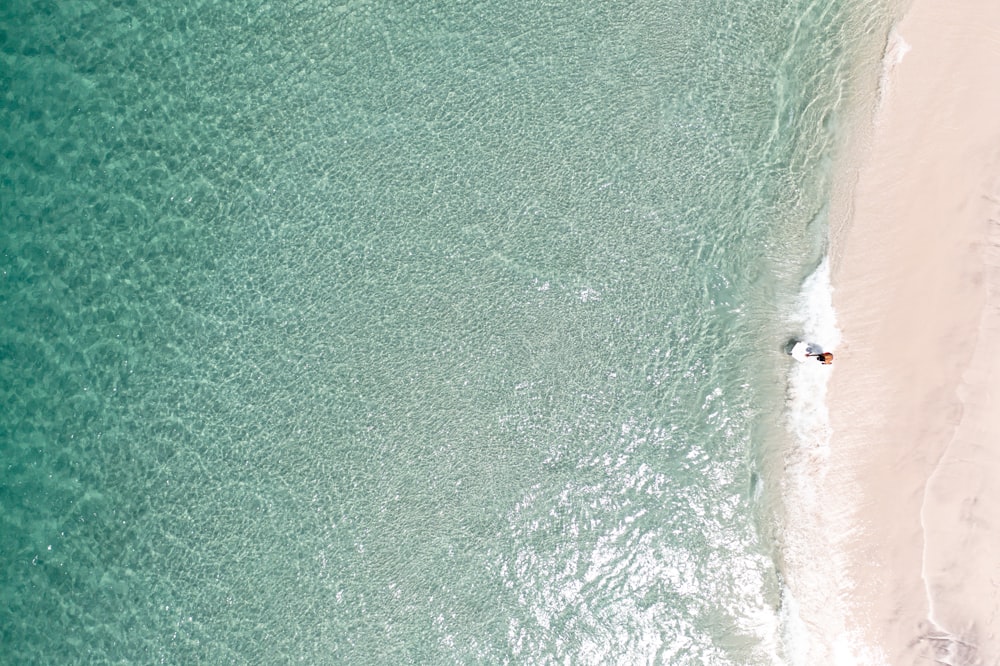 an aerial view of a beach with a boat in the water