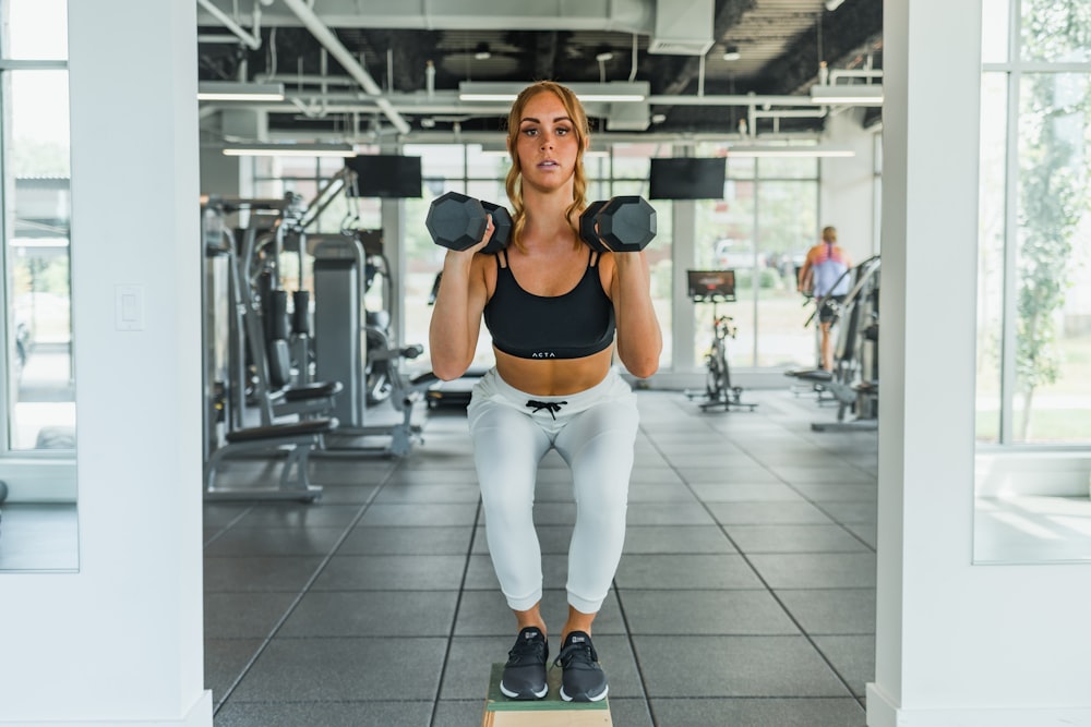 a woman standing on a block with a pair of dumbbells