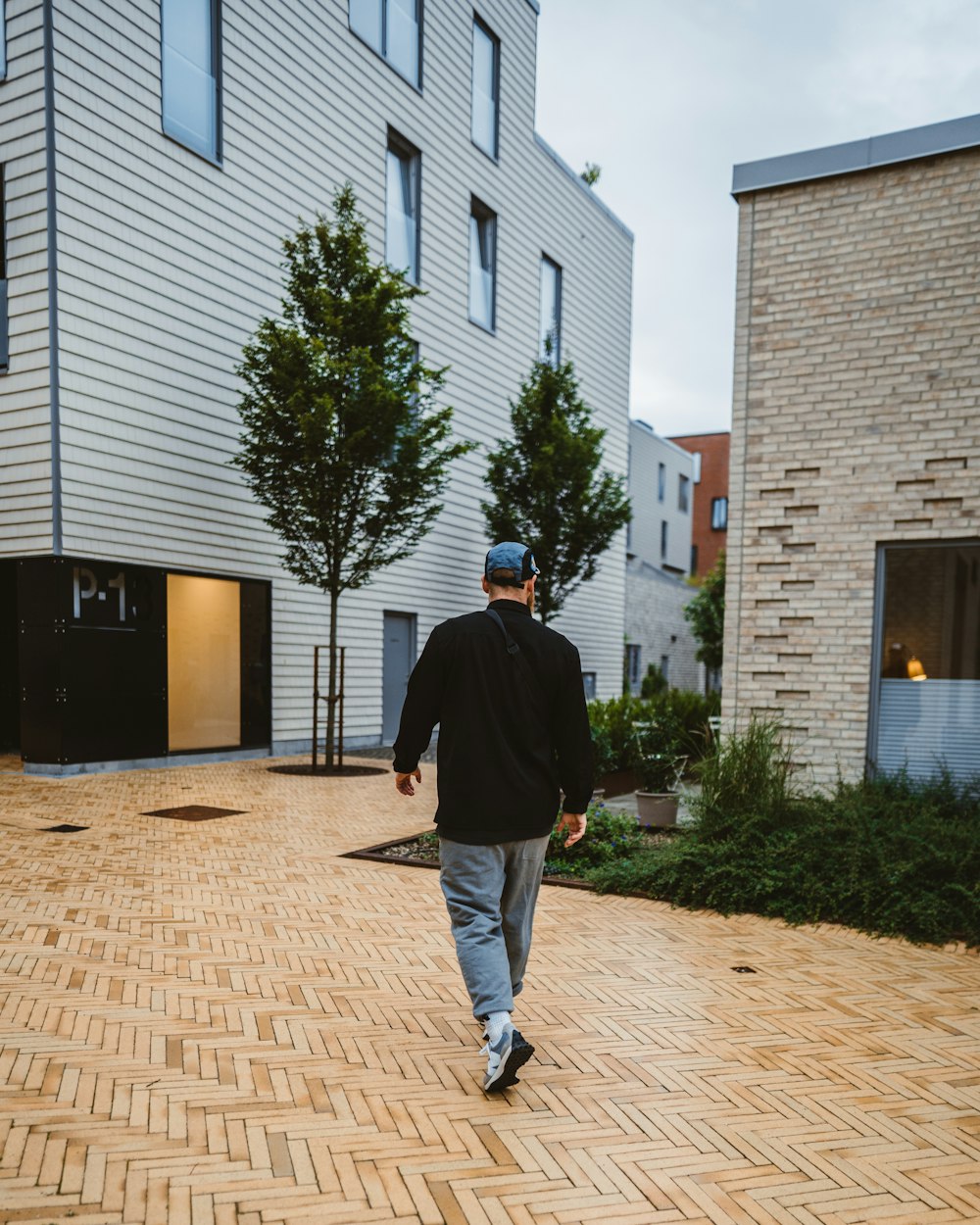 Un homme marchant sur une passerelle en briques devant un immeuble