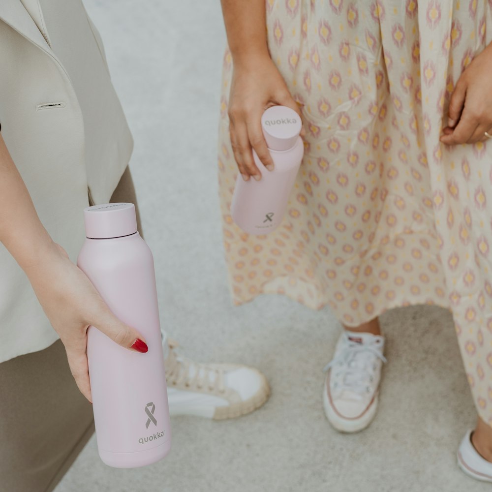 two women standing next to each other holding water bottles