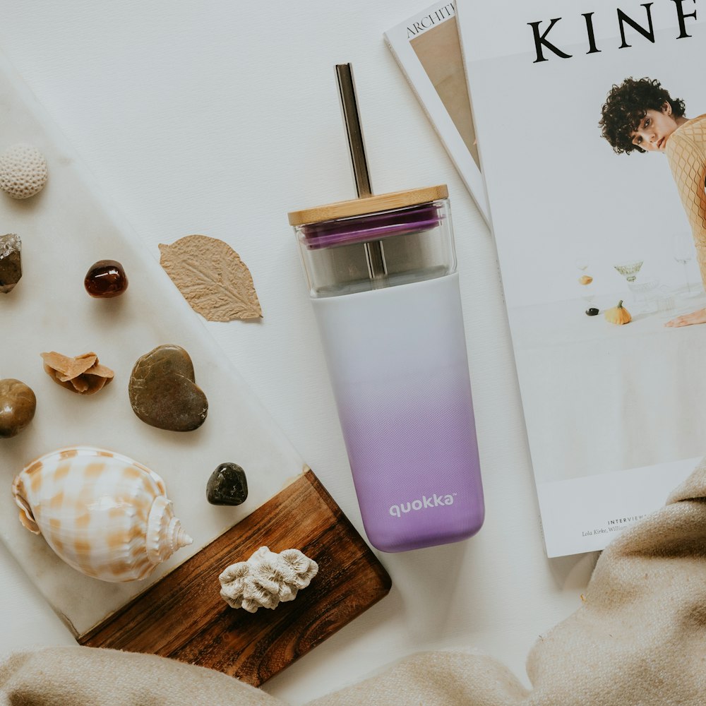 a purple and white water bottle next to a magazine