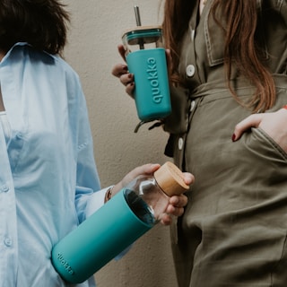 two women standing next to each other holding coffee mugs