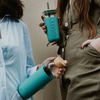 two women standing next to each other holding coffee mugs