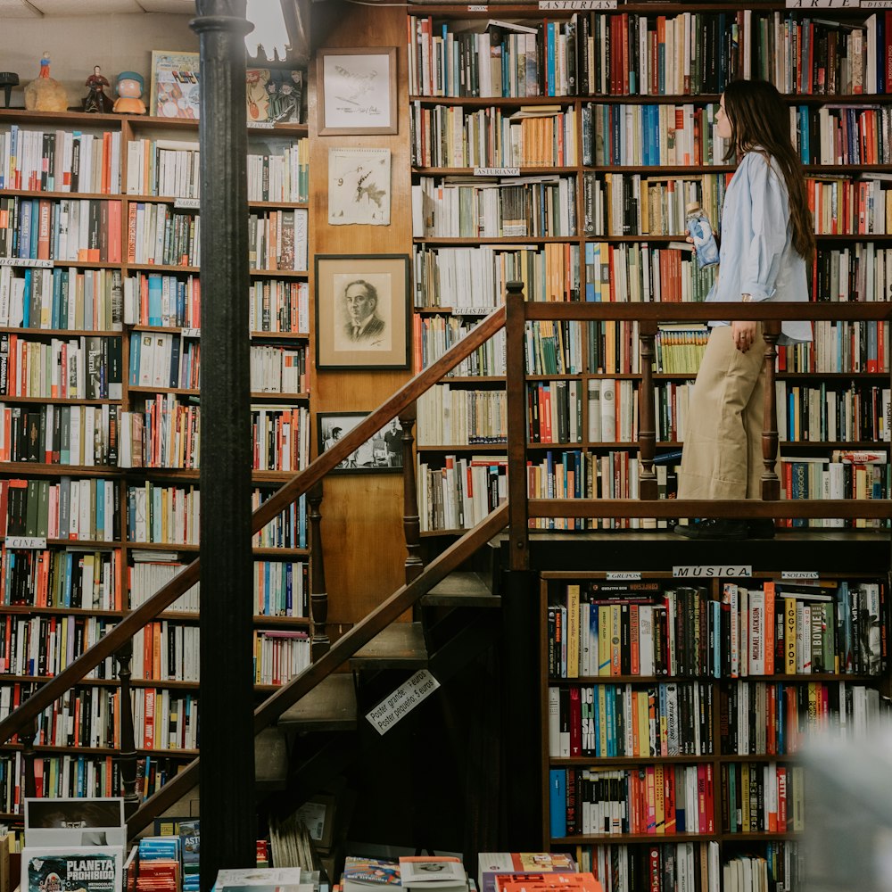 a woman standing on a stair case in front of a bookshelf