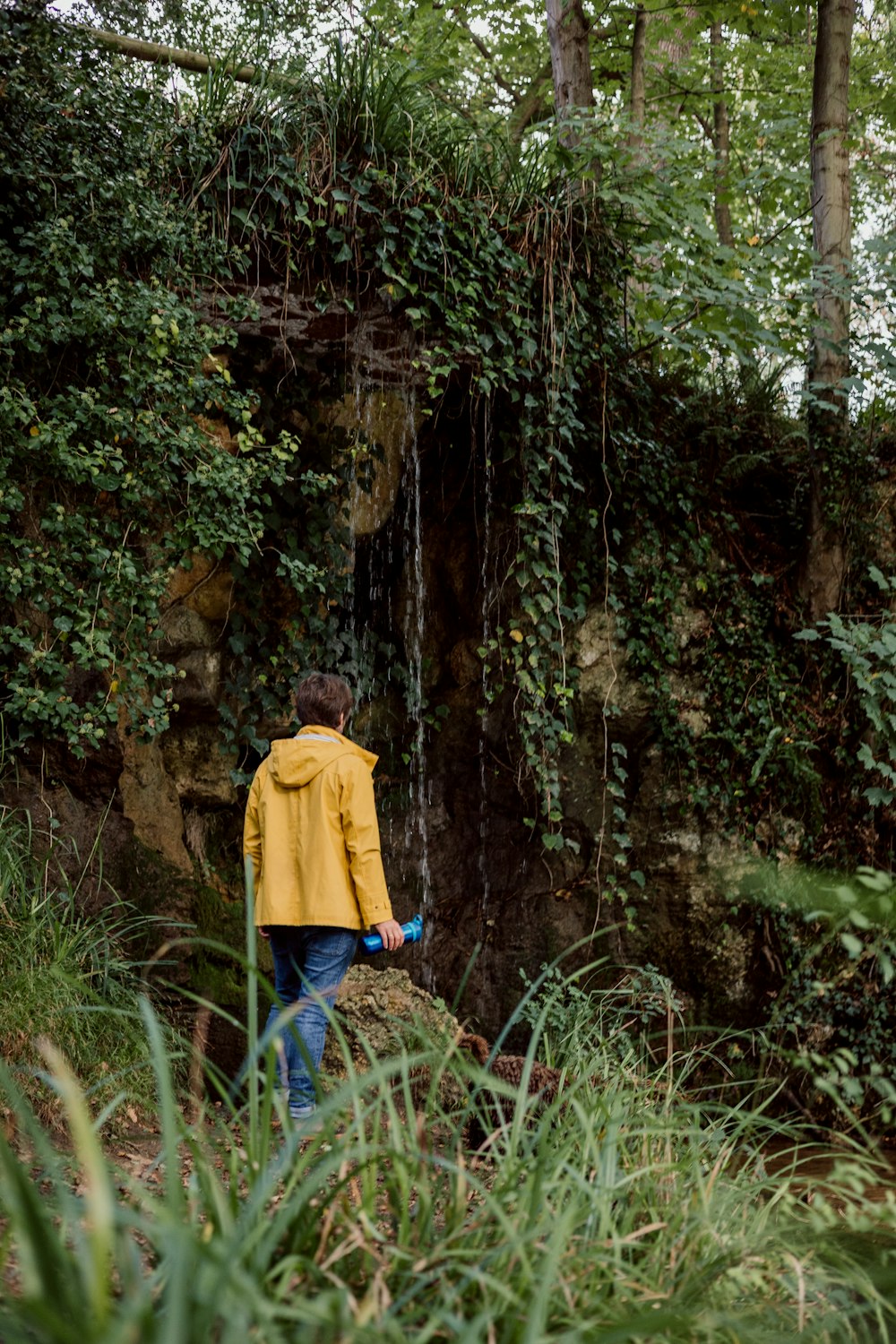 a man in a yellow jacket is standing near a waterfall