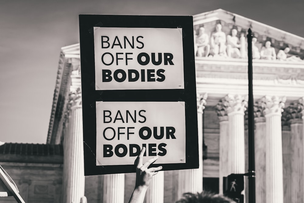 a person holding up a sign in front of a building