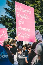 a group of people holding up pink signs