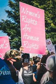 a group of people holding up pink signs
