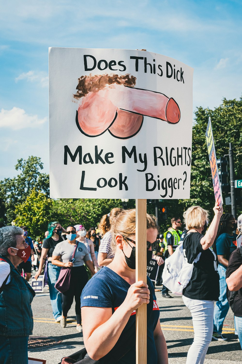 Eine Frau, die ein Schild hält, auf dem steht, dass dieser Schwanz meine Rechte größer aussehen lässt?