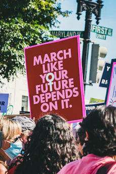 A protest sign reading 'Protect Florida's Future' held by a diverse group of concerned citizens in a sunny park.