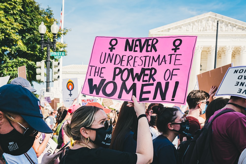 a group of people holding signs and wearing masks