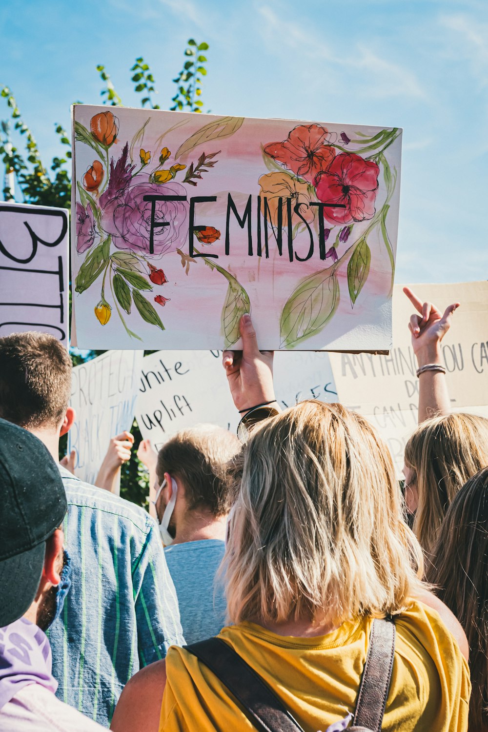 Eine Gruppe von Menschen hält ein Schild hoch, auf dem feministisch steht