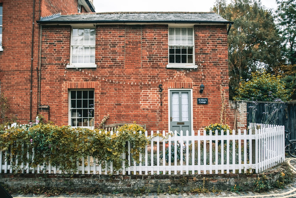 a brick house with a white picket fence