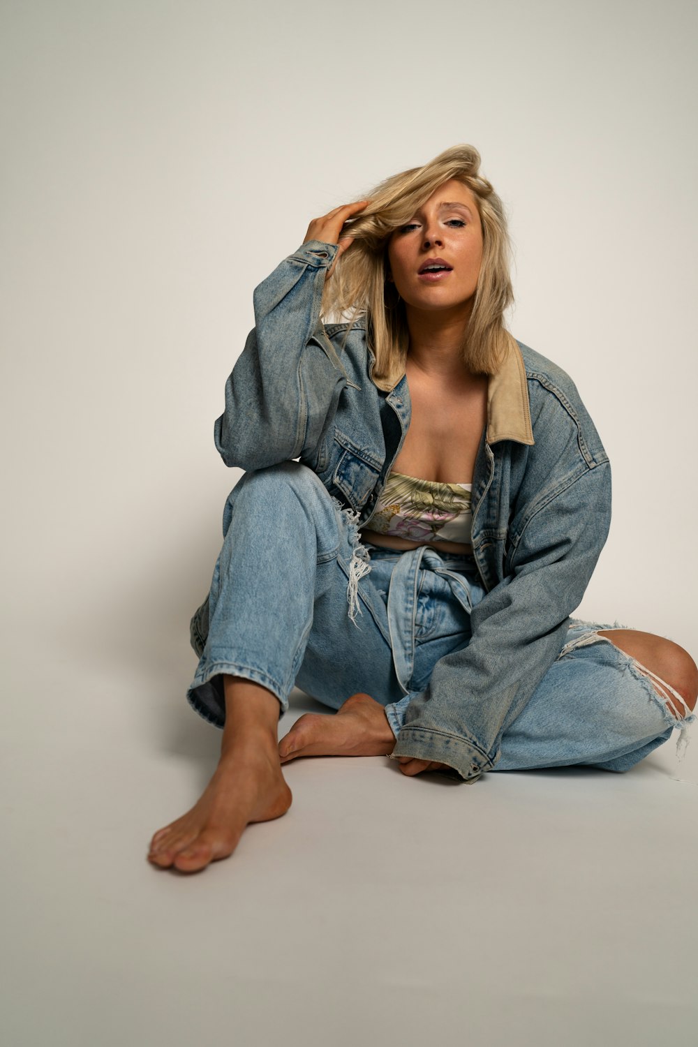 a woman sitting on the ground wearing a jean jacket