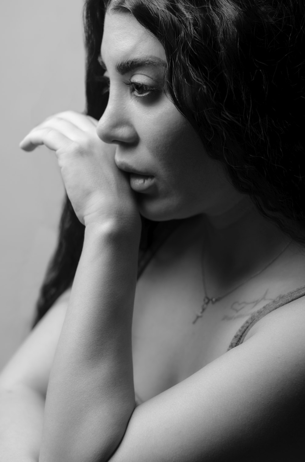 a black and white photo of a woman holding her hand to her face