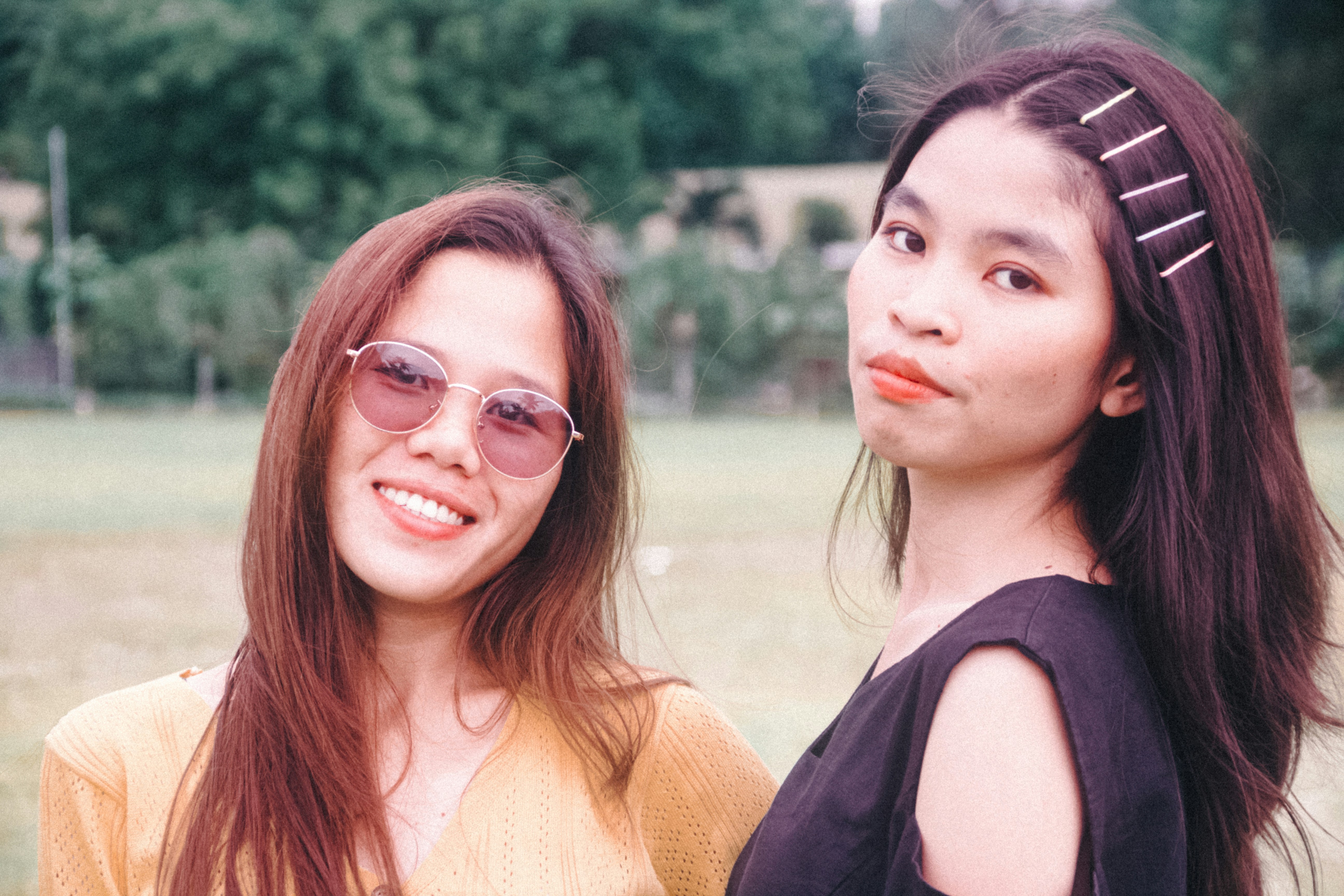 two women standing next to each other in a field